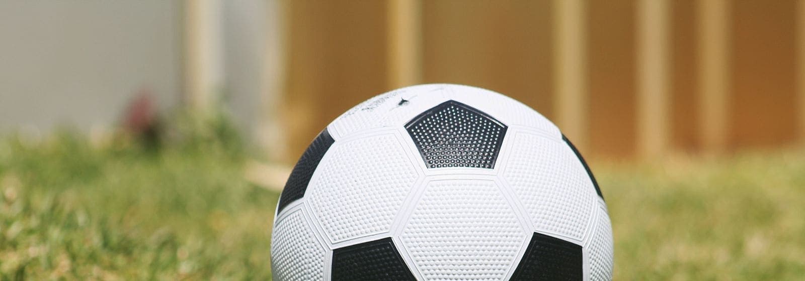 A black and white soccer ball resting on sunlit grass