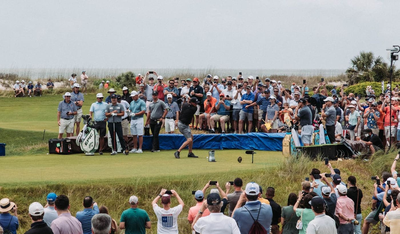 A large crowd of spectators gathered around a tee at a professional golf tournament