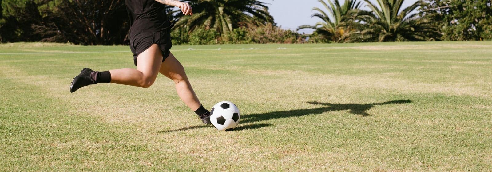 A player kicking a soccer ball across an open grass field