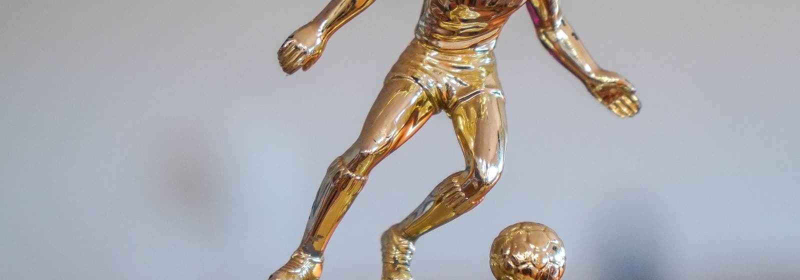 A golden trophy figurine of a soccer player about to kick a ball